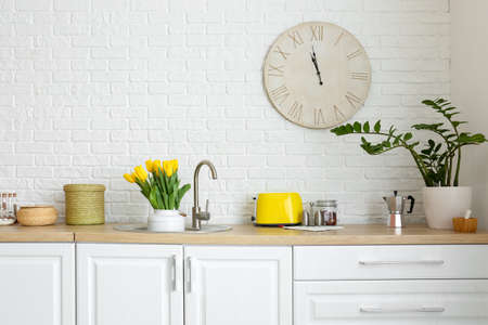 Interior of light kitchen with bouquet of tulips in sink