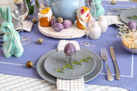 Holder with painted Easter egg and eucalyptus branch on served table