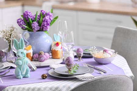 Holder with painted Easter egg and eucalyptus branch on served table