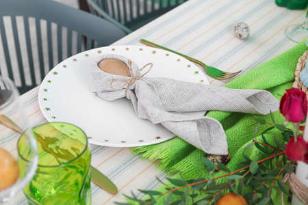 Plate with egg in Easter bunny napkin on served tableの写真素材