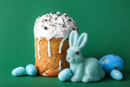 Cute Easter bunny with cake and painted eggs on green backgroundの写真素材