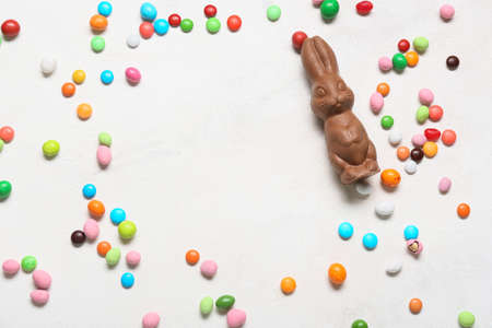 Frame made of colorful candies and Easter chocolate bunny on light background