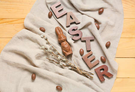 Composition with Easter chocolate bunny, candies and pussy willow branches on wooden backgroundの写真素材