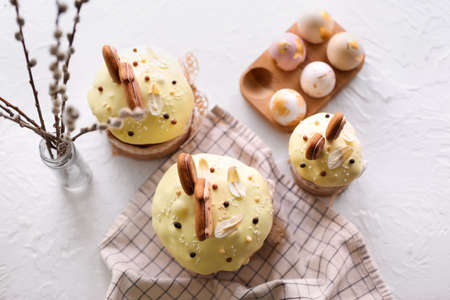 Delicious Easter cakes decorated with cookies, willow branches and painted eggs on light background