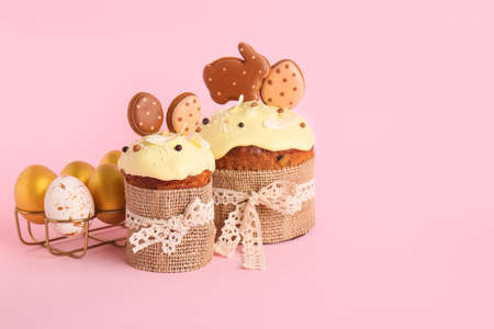 Delicious Easter cakes decorated with cookies and painted eggs on pink backgroundの写真素材