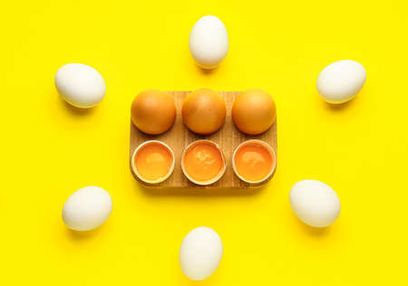 Holder with fresh chicken eggs on yellow background