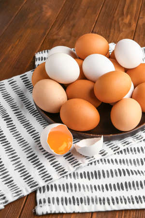 Plate with chicken eggs on wooden background, closeup
