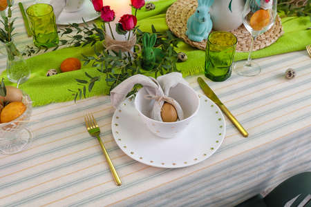 Stylish dinnerware and egg in napkin on table served for Easter celebration
