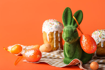 Cute Easter bunny, eggs and cakes on orange backgroundの写真素材