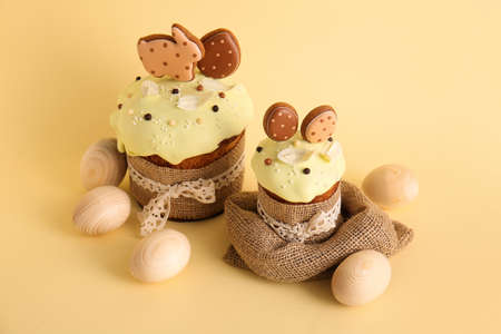 Delicious Easter cakes decorated with cookies and wooden eggs on beige background