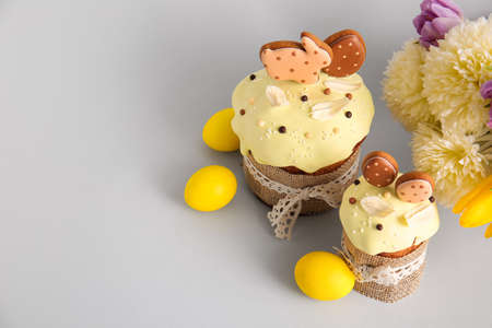 Delicious Easter cakes decorated with cookies, flowers and painted eggs on light background