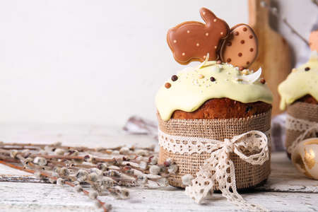 Delicious Easter cake decorated with cookies and willow branches on light background