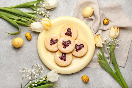 Beautiful Easter composition with tasty cookies, eggs and spring flowers on light background