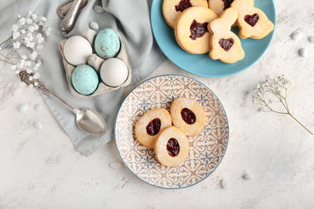 Beautiful Easter composition with tasty cookies, eggs and flowers on light backgroundの写真素材