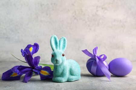 Cute Easter bunny with painted eggs and flower on light backgroundの写真素材