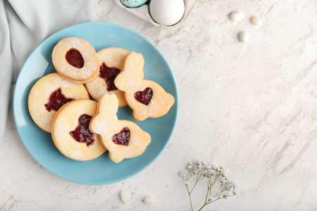 Plate of tasty Easter cookies on light background