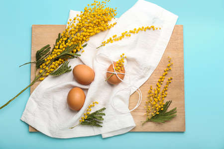Beautiful Easter composition with eggs and blooming mimosa branches on color backgroundの写真素材