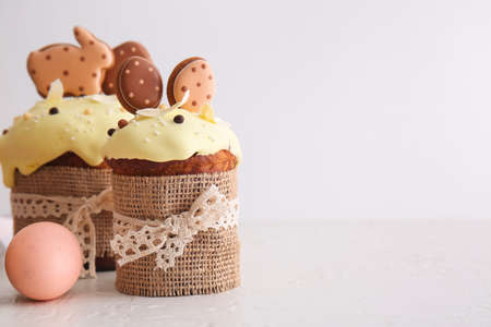 Delicious Easter cakes decorated with cookies and painted eggs on light background