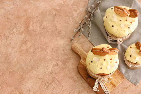 Tasty Easter cakes decorated with cookies on color background