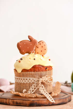 Wooden board with tasty Easter cake decorated with cookies on table, closeup