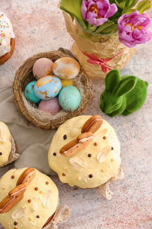 Tasty Easter cakes and nest with eggs on light background