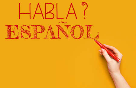 Hand writing text HABLA ESPANOL? (DO YOU SPEAK SPANISH?) on orange backgroundの写真素材