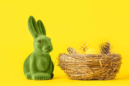 Green Easter bunny and nest with eggs on yellow backgroundの写真素材