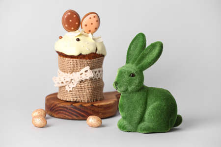 Green Easter bunny and tasty cake on white background