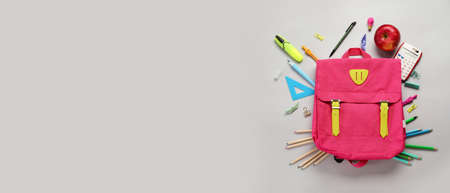 School backpack and stationery on gray background with space for textの写真素材