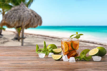 Glass of tasty Cuba Libre cocktail and ingredients on table at tropical resortの写真素材