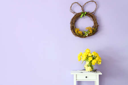 Table with magazines, tulips and beautiful Easter decor near color wall