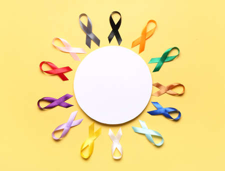 Composition with colorful awareness ribbons and blank card on yellow background. World Cancer Dayの写真素材