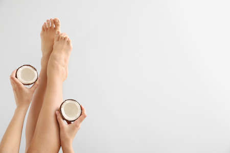 Legs of young woman with coconut on light backgroundの写真素材