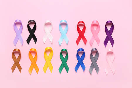 Different colorful awareness ribbons on pink background. World Cancer Day