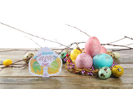 Painted Easter eggs and greeting card on table against white background