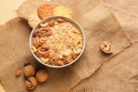 Bowl of healthy oatmeal with nuts on beige backgroundの写真素材