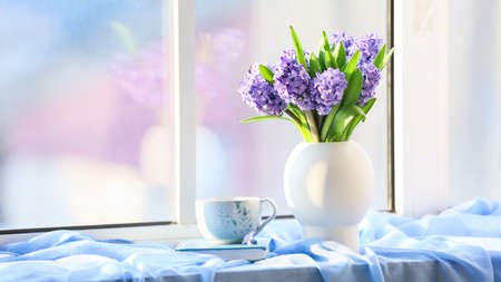 Vase with beautiful blooming hyacinths, book and cup of tea on windowsillの写真素材
