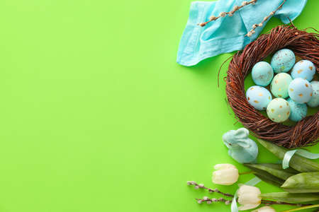 Nest with painted Easter eggs, tulip flowers and willow branches on green backgroundの写真素材