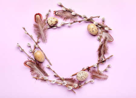 Stylish wreath with Easter eggs, willow branches and feathers on purple backgroundの写真素材