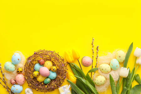 Painted Easter eggs, tulip flowers and willow branches on yellow backgroundの写真素材