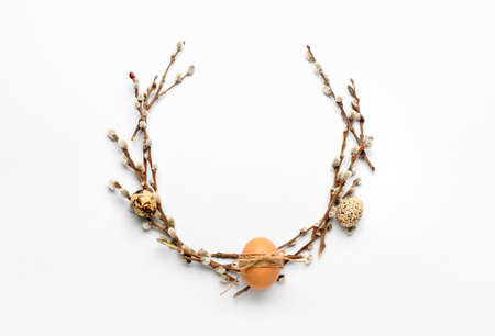 Stylish wreath with Easter eggs and willow branches on light backgroundの写真素材