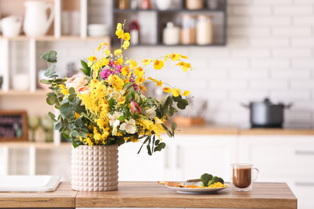 Vase with different beautiful flowers and breakfast on dining table in kitchenの写真素材