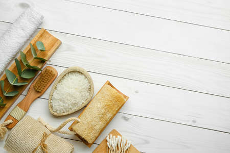 Set of bath supplies with sea salt on light wooden background