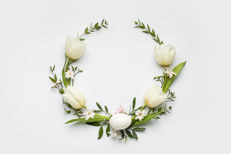 Stylish wreath with Easter egg and tulip flowers on light backgroundの写真素材