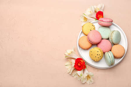 Composition with tasty macaroons and beautiful flowers on color background. International Women's Day celebrationの写真素材
