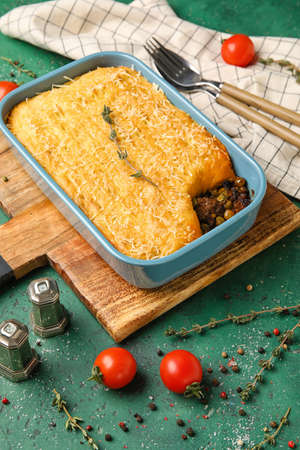 Baking dish with tasty Shepherd's pie on green background