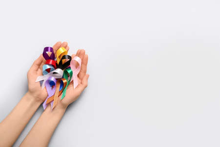 Female hands full of awareness ribbons on light background. World Cancer Dayの写真素材