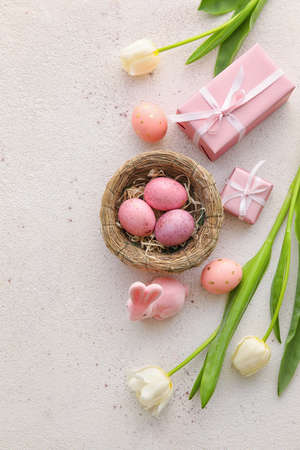 Composition with painted Easter eggs, gift boxes and tulip flowers on light background