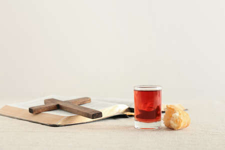 Glass of wine with bread, Holy Bible and cross on light backgroundの写真素材