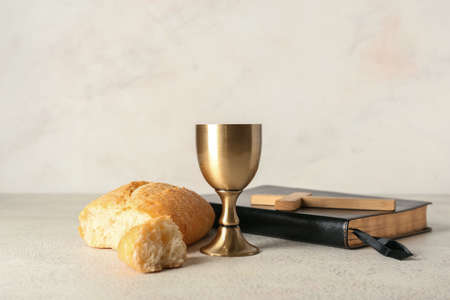 Cup of wine with bread, Holy Bible and cross on light backgroundの写真素材